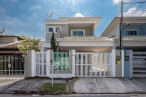 een witte poort voor een huis bij Casa incrível com 04 suítes - 5 min de Itacoatiara in Niterói