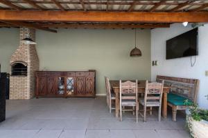patio con mesa, sillas y TV en Casa incrível com 04 suítes - 5 min de Itacoatiara, en Niterói