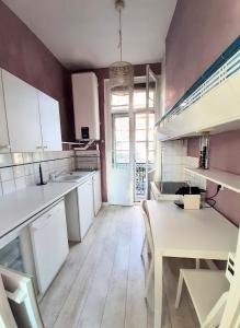 a large kitchen with white cabinets and a table at Appartement Pont des Catalans in Toulouse