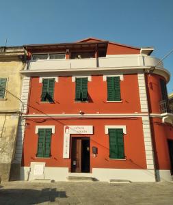 un edificio naranja con persianas verdes en una calle en Alla Porta Di Sotto B&B en Fivizzano