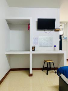 Zimmer mit einem Schreibtisch und einem TV an der Wand in der Unterkunft เกรซรูม รีสอร์ท (Grace Room Resort) 