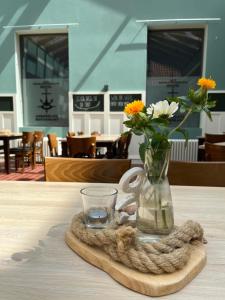 een vaas met bloemen en een glas op een tafel bij Hotel Alte Navigationsschule in Rhauderfehn