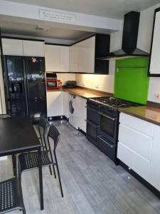 a kitchen with black and green appliances and a table and chairs at Ballintoy house with great sea views in Ballintoy