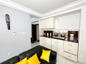sala de estar con sofá negro y almohadas amarillas en Studio Cosy centre AKWA, en Douala