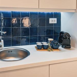 - un comptoir de cuisine avec évier et carrelage bleu dans l'établissement BLUE LUXURY SUITES, à Prévéza