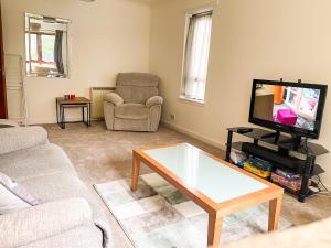 ein Wohnzimmer mit einem Sofa und einem TV in der Unterkunft Spacious, central and newly decorated apartment in Edinburgh