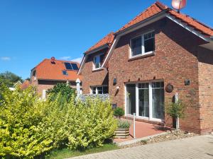 a brick house with bushes in front of it at harle-casa.ostfriesland in Altfunnixsiel
