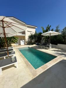 a swimming pool with two umbrellas and two chairs at KATINA'S DREAM HOUSE IN PELOPONNESE in Aigio