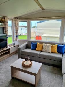 a living room with a couch and a coffee table at Modern Family Caravan with WiFi at Valley Farm, Clacton-on-Sea in Great Clacton