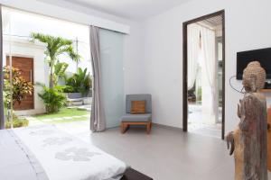 a bedroom with a bed and a chair in it at Villa KMEA 4 in Seminyak