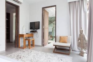 a living room with a tv and a chair and a mirror at Villa KMEA 4 in Seminyak
