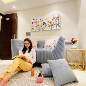 a woman sitting on a bed reading a book at ZEN Suites Gurgaon - LUXE Stays Collection in Gurgaon