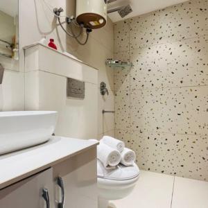 a white bathroom with a toilet and a shower at ZEN Suites Gurgaon - LUXE Stays Collection in Gurgaon