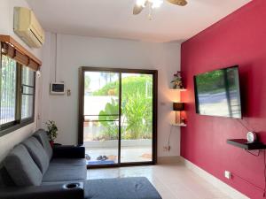sala de estar con sofá y pared roja en THAIGO Comfort Stay - Private House in Central Kanchanaburi, en Kanchanaburi