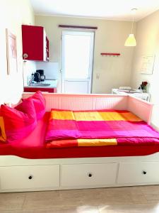 ライプツィヒにあるdie Senfbude - Klein aber fein - wunderschönes Studio-Apartment mit Terrasse und Stellplatzの赤い色とりどりの毛布が敷かれたベッド