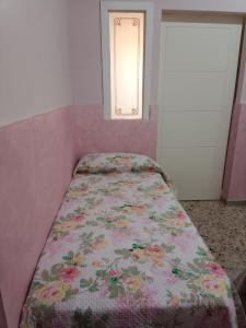 uma cama num quarto cor-de-rosa com um cobertor de flores em Holiday home La Rinascita em Bagheria