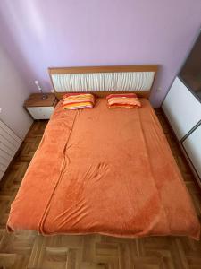 a bedroom with a bed with orange sheets and two pillows at Apartman JAGODA in Varaždin