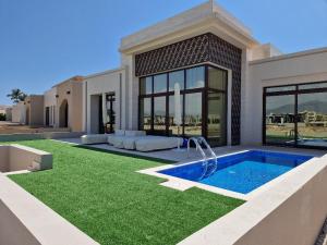 a villa with a swimming pool and a house at Glory Salalah Miko 1 in Salalah