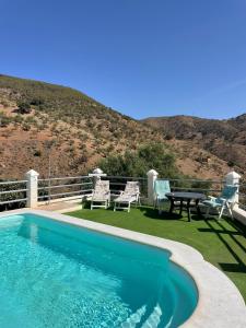 una piscina con tavolo e sedie su un patio di Casa rural Las Casillas a Málaga