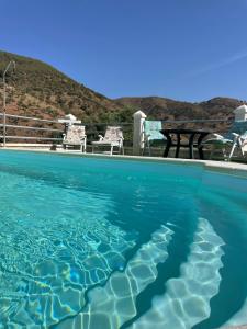 una piscina d'acqua con un tavolo da picnic sullo sfondo di Casa rural Las Casillas a Málaga