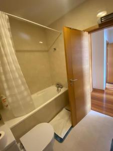 a bathroom with a toilet and a bath tub at Ferrara Rooms in Paços de Ferreira