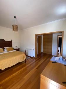 um quarto com uma cama e piso em madeira em Ferrara Rooms em Paços de Ferreira