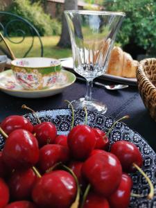 un tavolo con un piatto di ciliegie e un bicchiere di La Maison de Ville a Compiègne