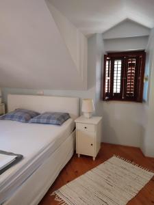 1 dormitorio con 1 cama, mesita de noche y ventana en Villa Rustika, en Sutivan