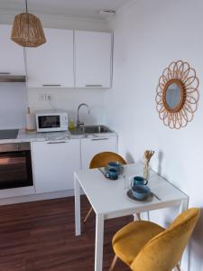 - une cuisine blanche avec une table et des chaises blanches dans l'établissement Appartement Cosy - Deux pièces - Hyper centre, à Auxerre