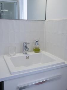 La salle de bains est pourvue d'un lavabo blanc et d'un miroir. dans l'établissement Appartement Cosy - Deux pièces - Hyper centre, à Auxerre