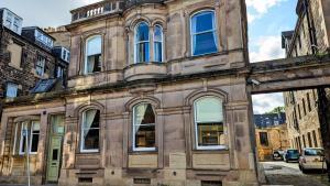 ein altes Gebäude mit blauen Fenstern auf einer Stadtstraße in der Unterkunft 89 The Merchants by The House of Danu in Edinburgh