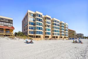 - un bâtiment sur la plage avec des gens sur le sable dans l'établissement Madeira Vista 201, à St. Pete Beach