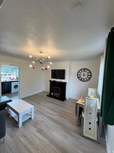 a living room with a table and a clock on the wall at 2 Bedrooms house,kitchen,bathroom,free parking in Mount Vernon