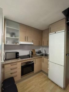 cocina con armarios de madera y nevera blanca en Sweet Home, en Esplugues de Llobregat