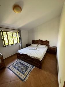 1 dormitorio con cama, ventana y alfombra en Sibora Guest House Liqeni Ulez, 