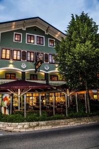 un gran edificio verde con un árbol delante de él en Pension Café Maier en Golling an der Salzach