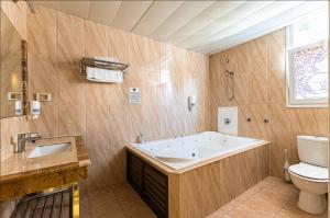 a bathroom with a tub and a toilet and a sink at Spa House Boutique Hotel - Petach Tikwa in Petaẖ Tiqwa