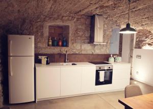 - une cuisine avec des appareils blancs et un mur en pierre dans l'établissement La Dolce Vita. Boutique Apartment, à Gérone