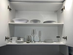a white shelf with glasses and plates and wine glasses at COMPLEJO VICTORIO in San Luis