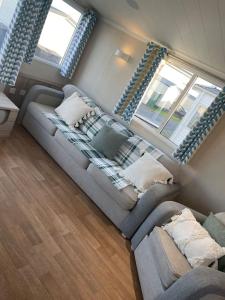 a living room with a couch and two windows at 2 bedroom (sleeps 6) caravan to rent in allonby in Maryport