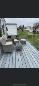 a deck with couches and a table and chairs at 2 bedroom (sleeps 6) caravan to rent in allonby in Maryport