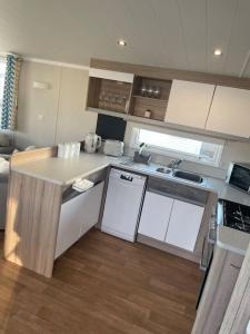 a kitchen with white cabinets and a counter top at 2 bedroom (sleeps 6) caravan to rent in allonby in Maryport