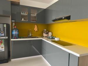 cocina con armarios grises y pared amarilla en Chi Homestay Nera Garden Huế, en Hue