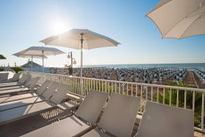 un balcone con sedie e ombrelloni su una spiaggia di Hotel Canarie a Lido di Jesolo