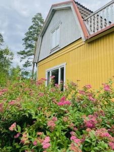 una casa amarilla con flores rosas delante en Mark Villan en Örebro