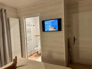Le mas des anges في Soussans: غرفة بها تلفزيون على الحائط وسرير