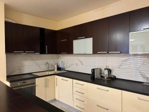 a kitchen with white cabinets and black counter tops at Sandras Apartment in Strumica