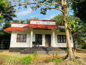 uma pequena casa branca com um telhado vermelho em VayalMonk - Alleppey Island Isolated Villa resort em Alappuzha