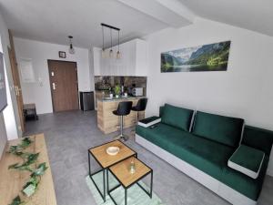 a living room with a green couch and a table at Apartament Apres Ski in Karpacz