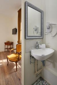 uma casa de banho com um lavatório, um espelho e uma cadeira em Hôtel De France Et De Guise em Blois